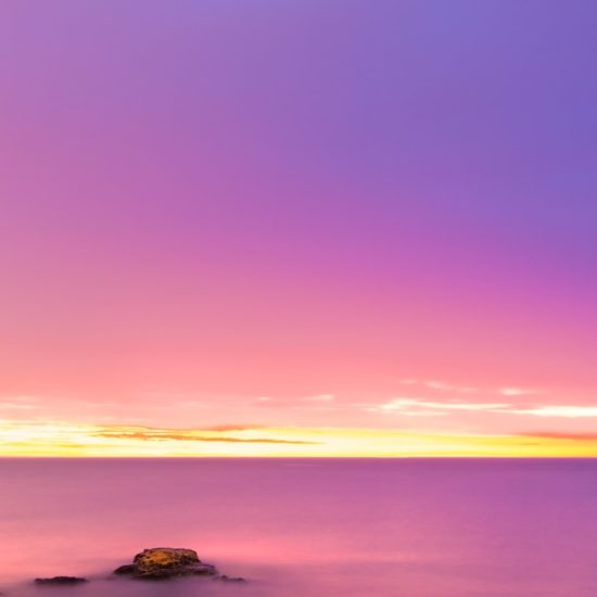 rock formation on body of water during sunrise